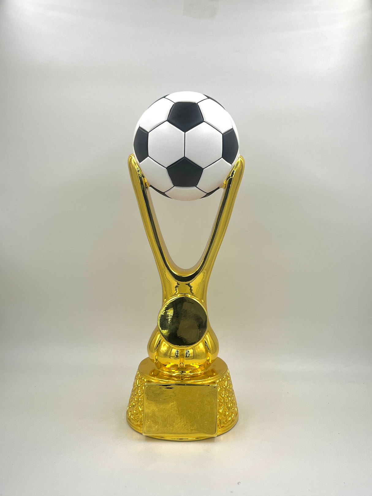Gold trophy with a black and white soccer ball on top against a white background.