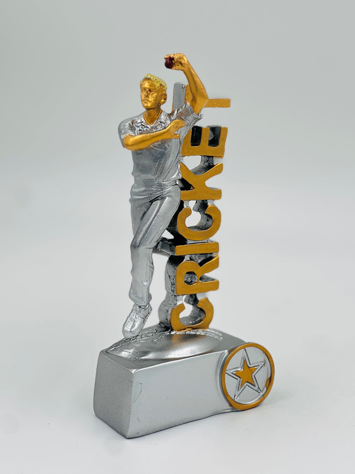 Detailed silver cricket trophy showing a player figure in mid-bowling action, standing beside the vertical "CRICKET" text on a heavy base.