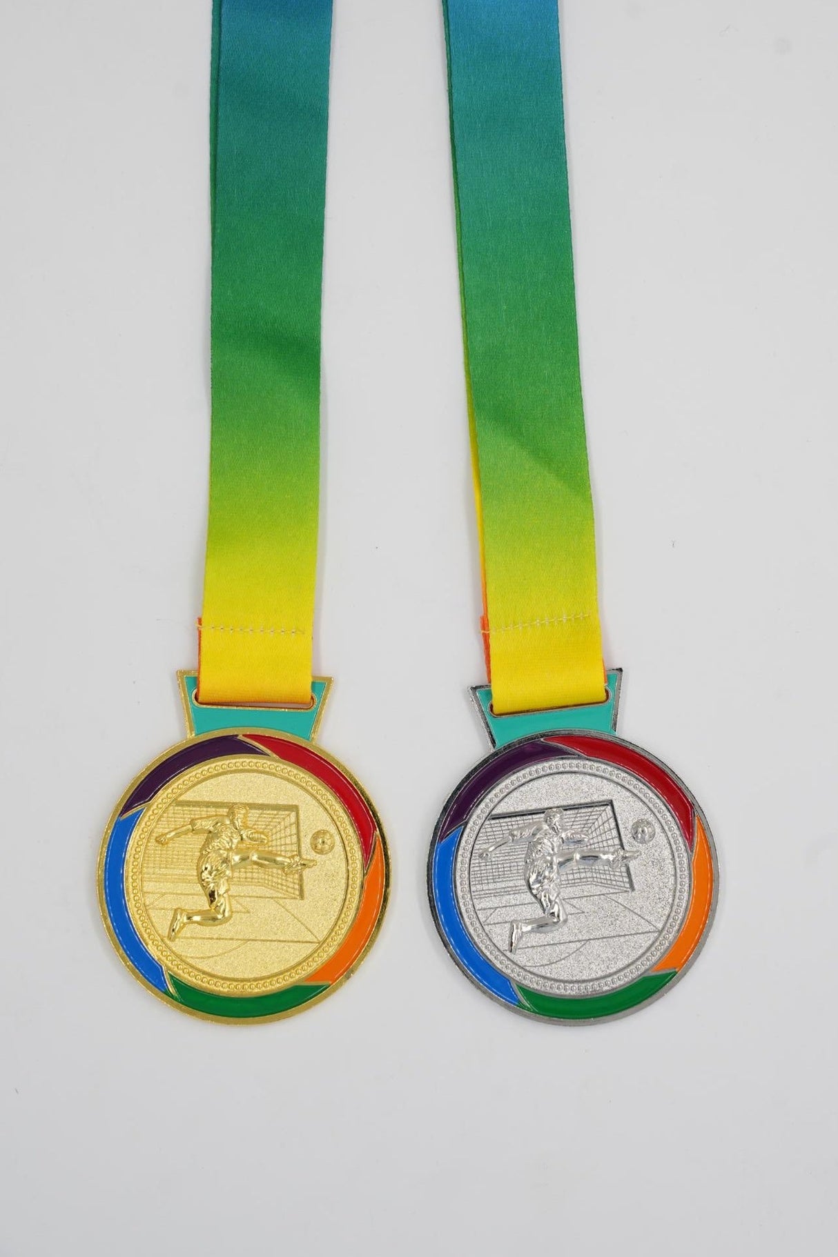 Gold and silver football medals with rainbow ribbon for winners