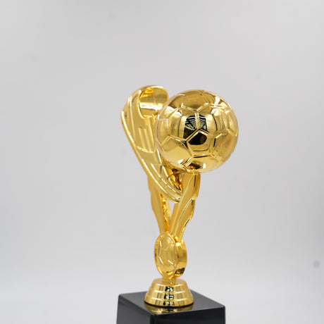 Close-up of the shiny gold soccer cleat and football at the top of the sports champion award.