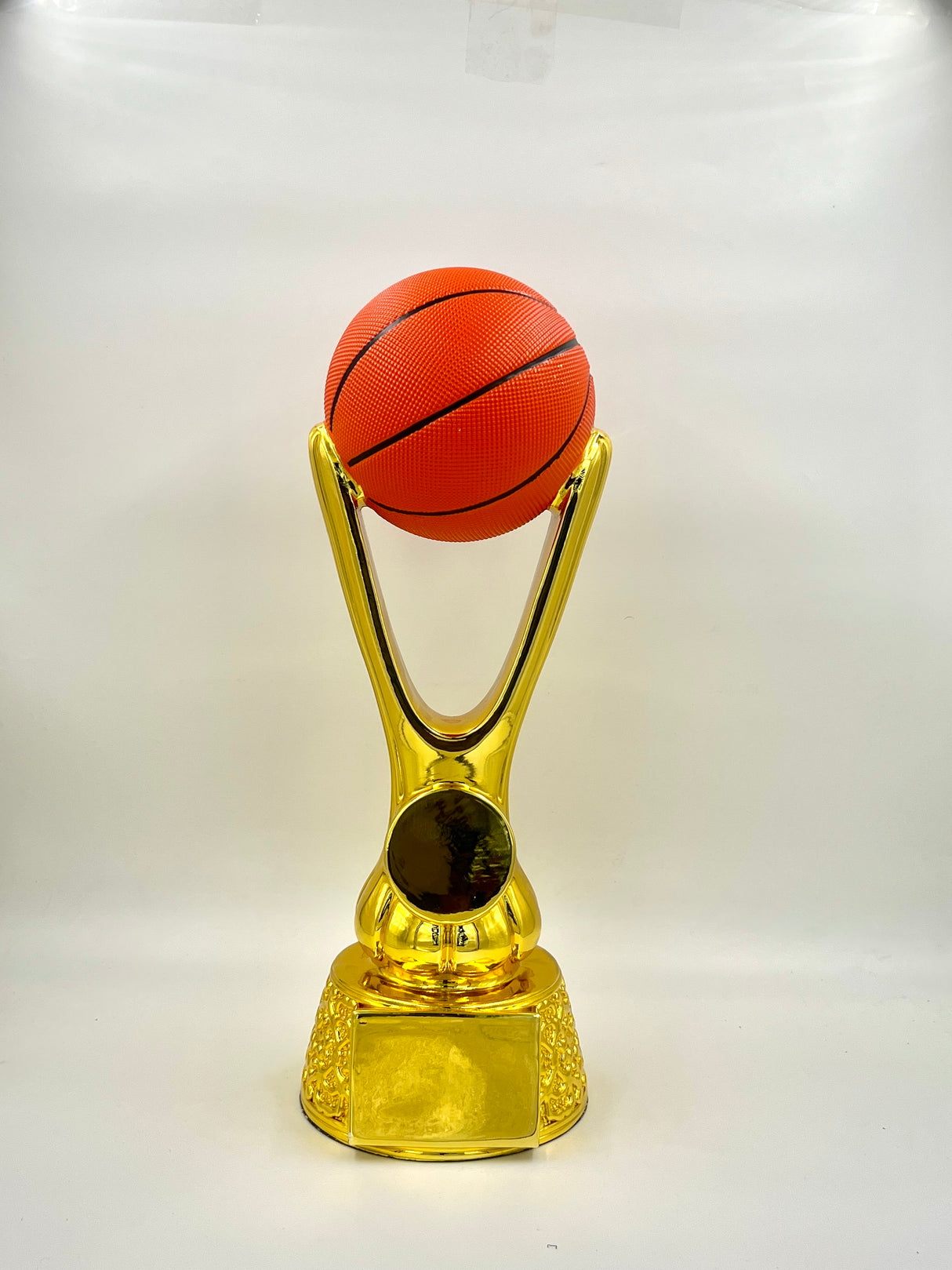 Gold trophy with an orange basketball on top against a white background.