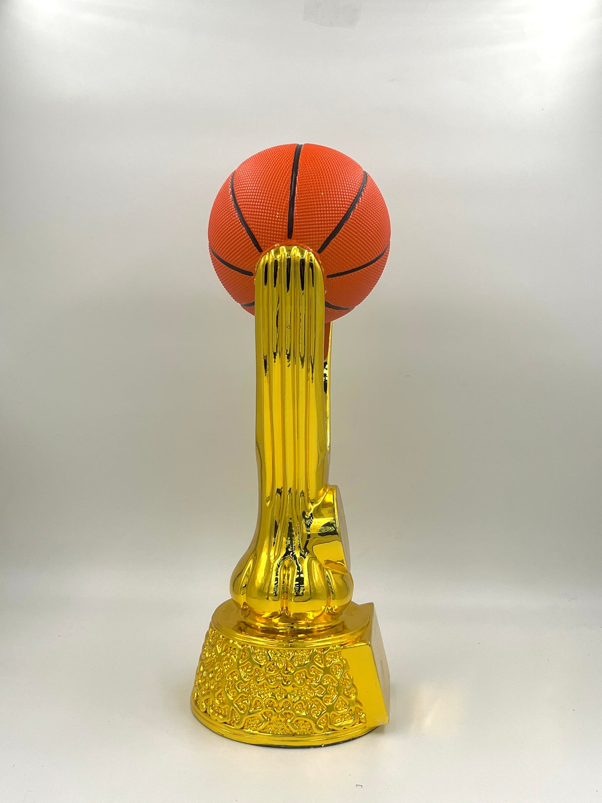 Shiny metallic gold trophy featuring a realistic textured basketball and a dynamic riser.
