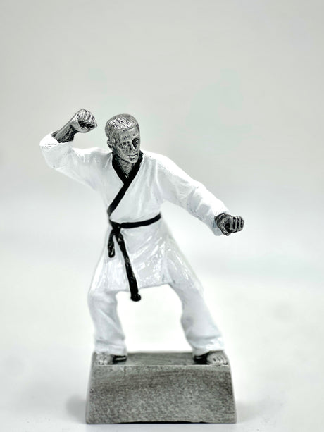 Silver martial arts trophy statue in a fighting pose with a black belt on a gray base.