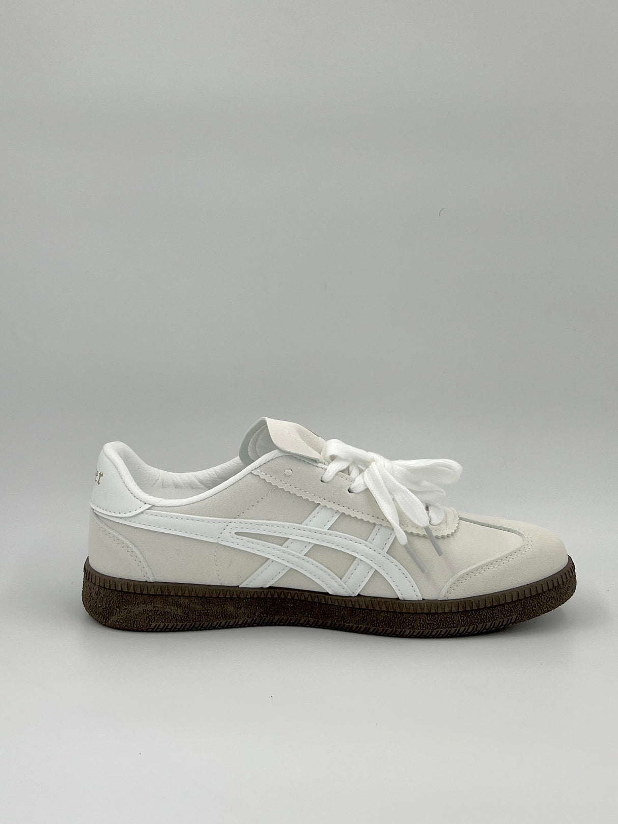 White sneaker with a brown sole on a light gray background