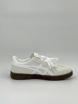 White sneaker with a brown sole on a light gray background