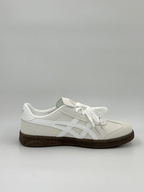 White sneaker with a brown sole on a light gray background