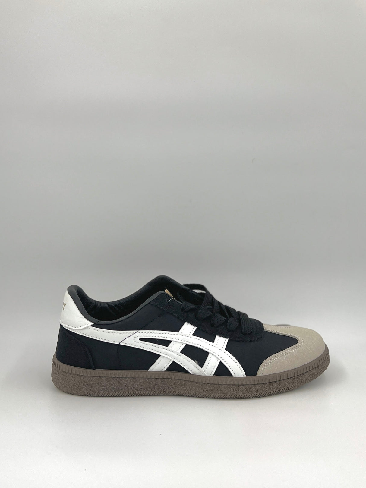 Black and white sneaker with a gray sole on a light gray background