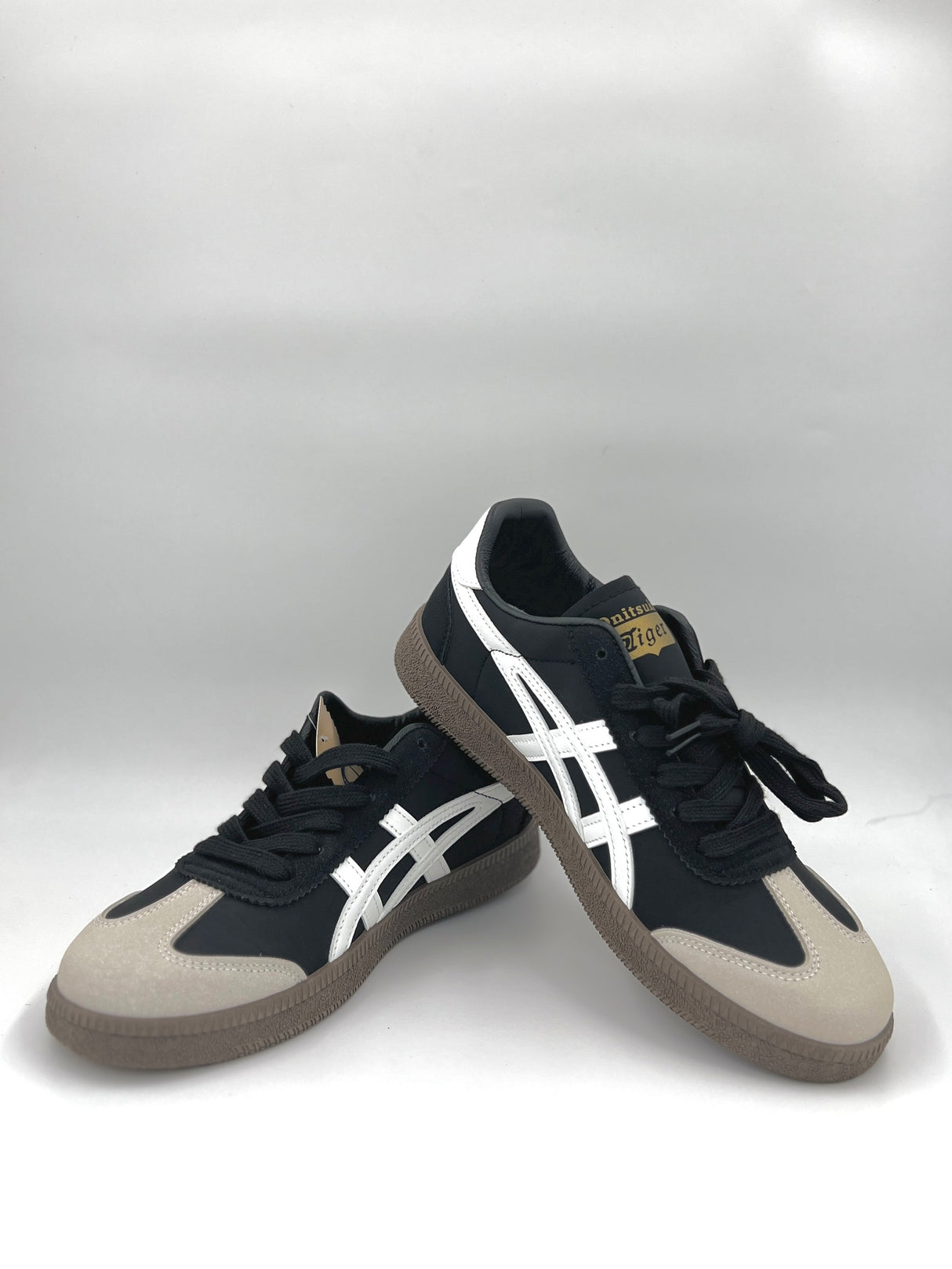 Black and white sneakers with beige accents on a white background